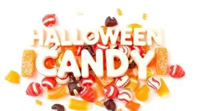 White 3D letters spelling out "HALLOWEEN CANDY" are arranged on top of a pile of assorted Halloween candies, including gummy candies and striped hard candies.
