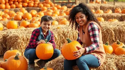 A smiling woman and a young boy crouch down in a pumpkin patch, holding large orange pumpkins. They are surrounded by hay bales and many more pumpkins, suggesting a festive autumn atmosphere.