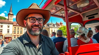 A man wearing a cowboy hat and glasses smiles at the camera while riding on a red open-top bus through a European town.